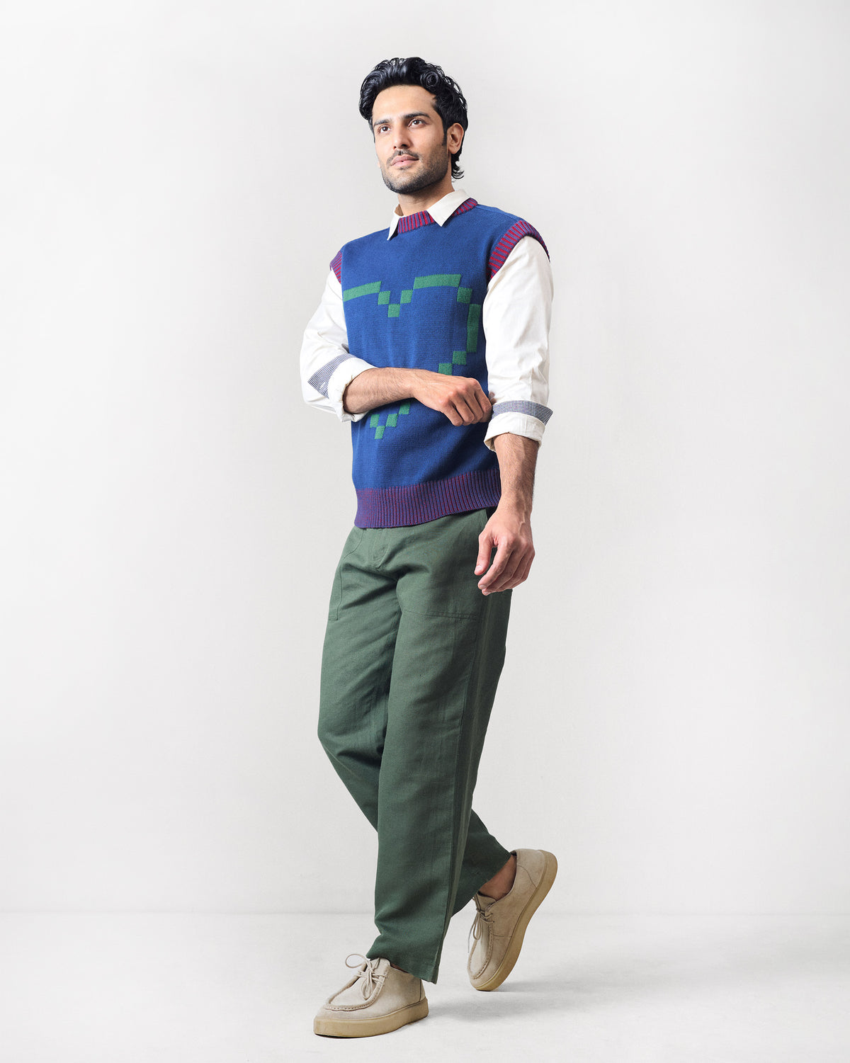 Person wearing a navy sleeveless Pixel Sweater with a green pixel heart.