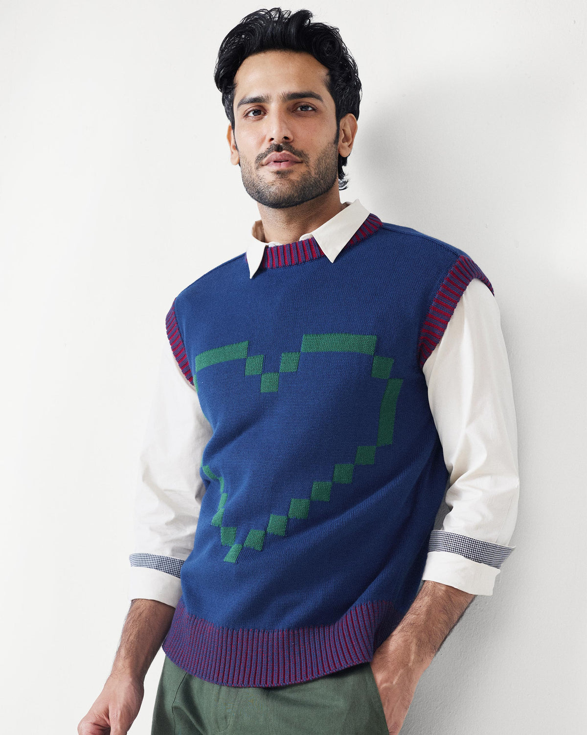 Person wearing a navy Pixel Sweater with a green pixel heart on the chest.