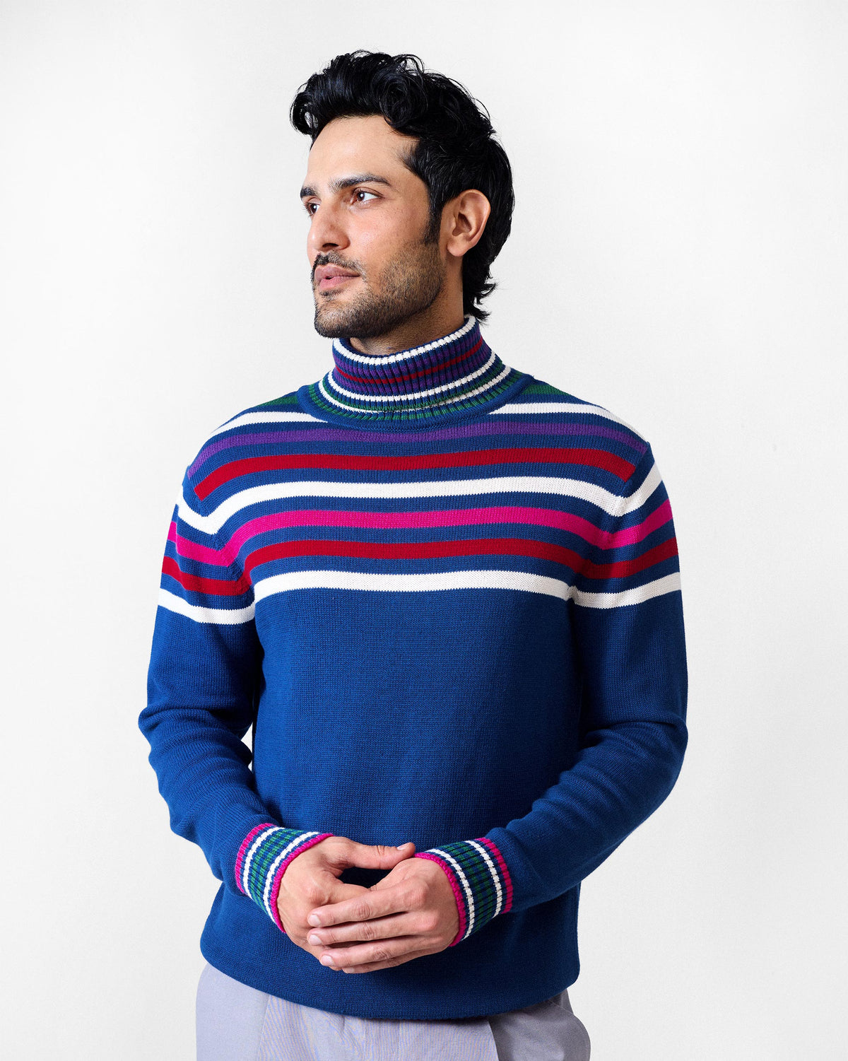 Person wearing a navy Ringer sweater with striped cuffs and a turtleneck collar.