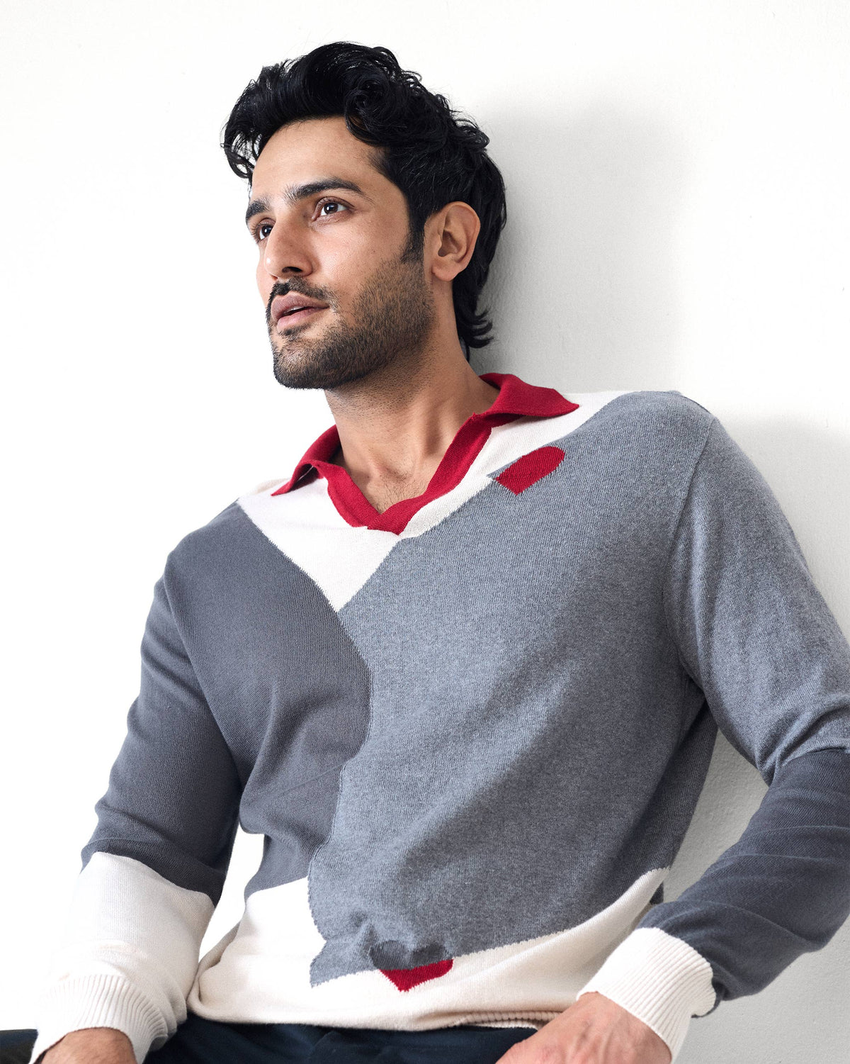 Person wearing a grey Dom Sweater with a red V-neck polo collar.