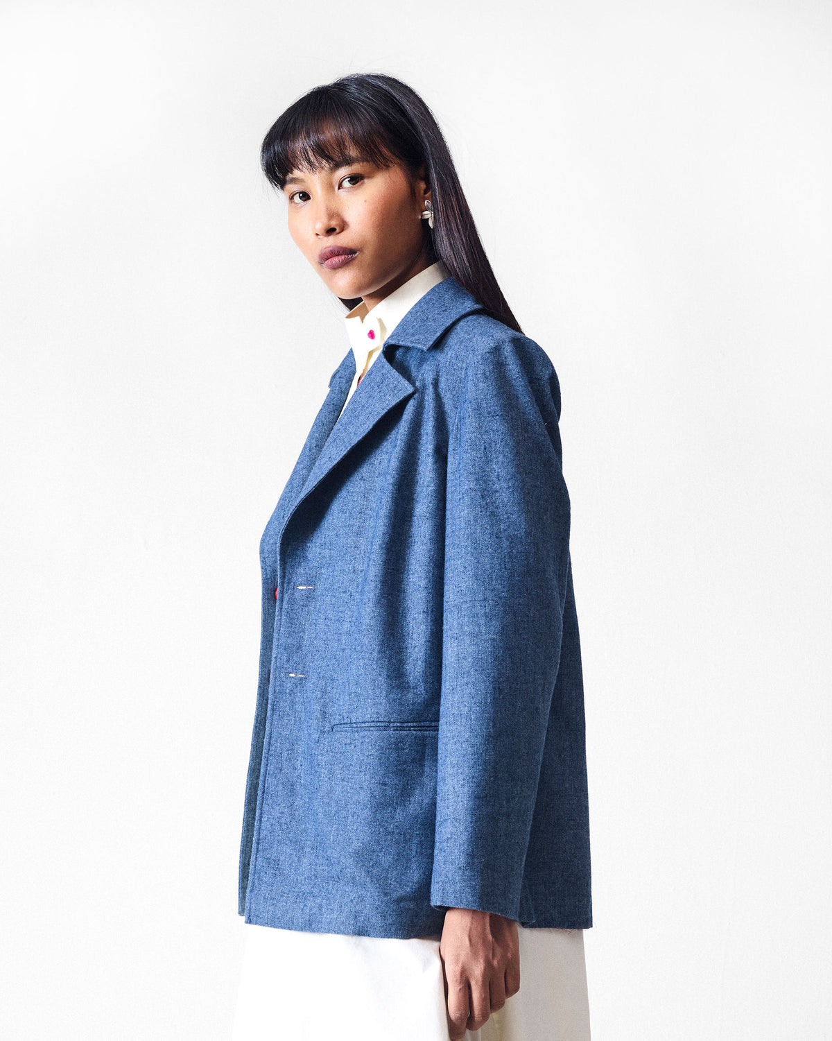 Side view of a dust blue Trace Jacket with notched lapels and welt pockets.