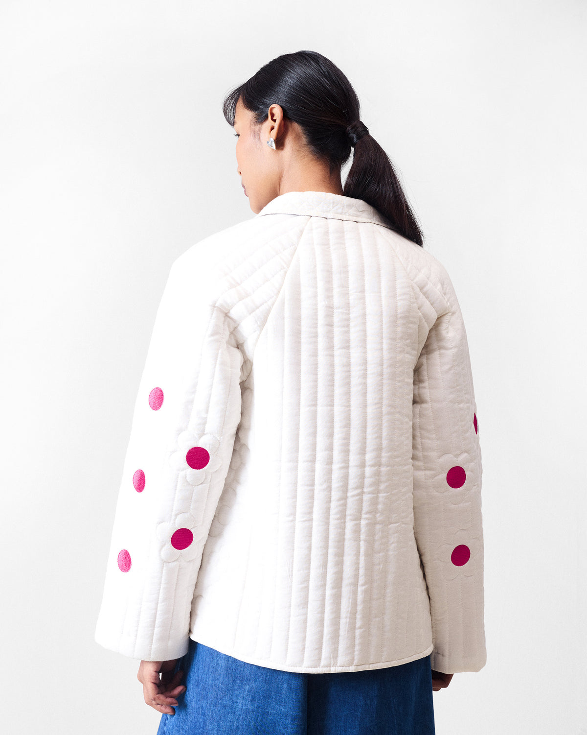 Back of an ivory quilted Botanik jacket with fuchsia accents on the sleeves.