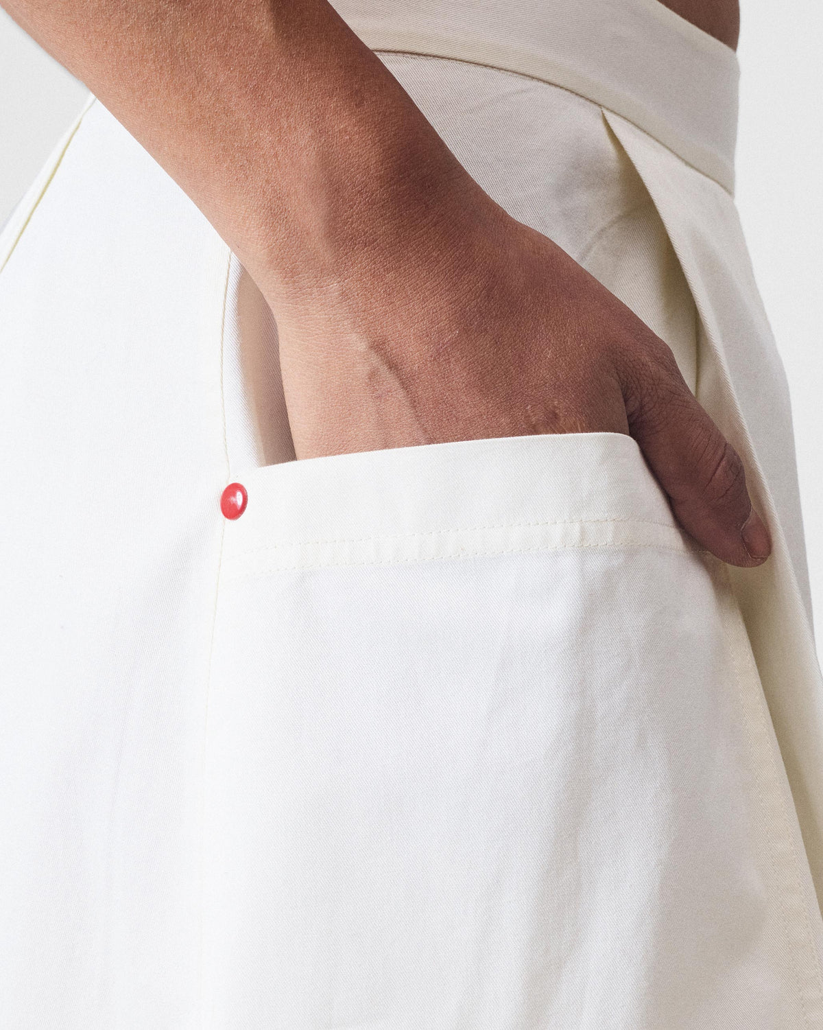 Close-up of the ivory Twirl skort pocket with a red button accent.