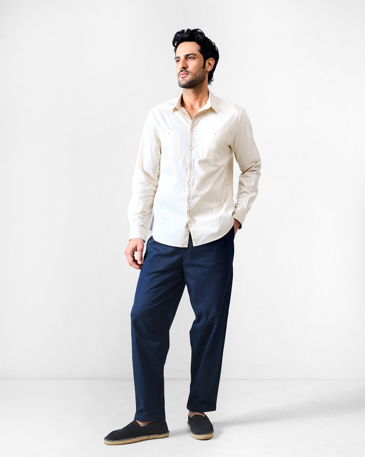 Ivory Abe shirt worn full length with navy trousers.
