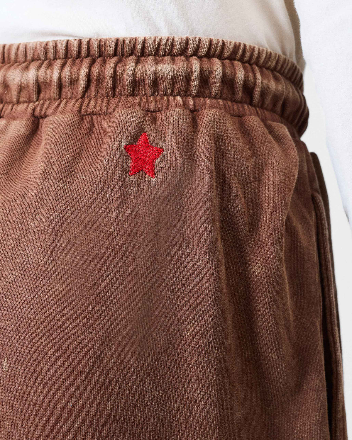 Close-up of a red star embroidered on brown Drift bottoms.