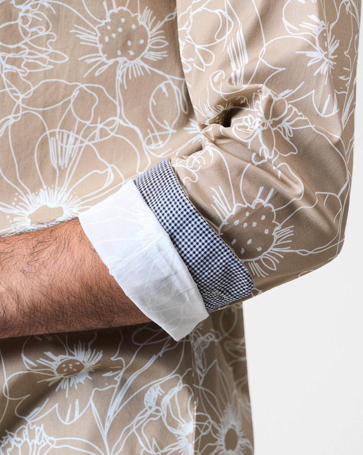 Close-up of a light brown Hakuna Shirt cuff with floral print and check lining.