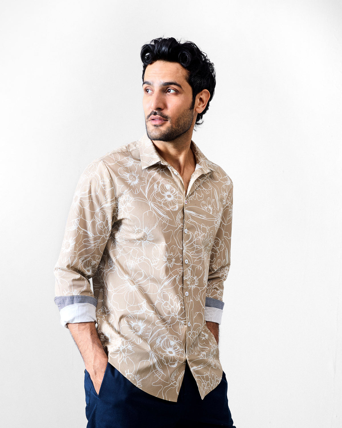 Person wearing a light brown Hakuna Shirt with a white floral print.