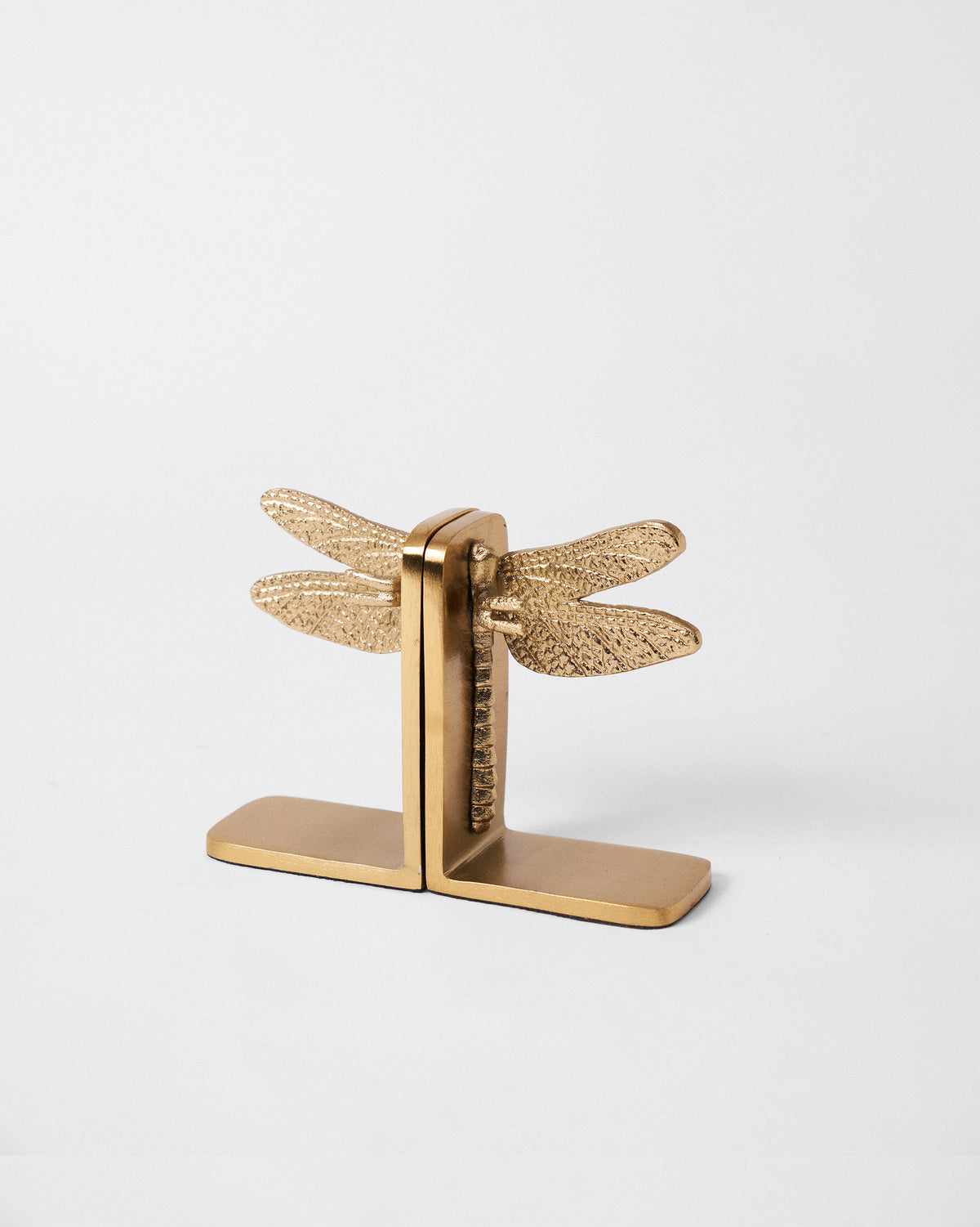 Angled view of gold dragonfly bookends showing hammered wing texture and bases.