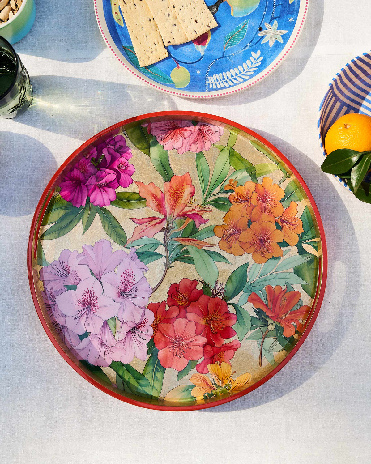 Blooming Flower round tray with red rim on a sunlit dining table.