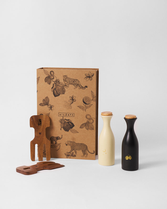 Chand Ambi Oil Pourer & Servers Set with cream and black pourers and wooden servers.