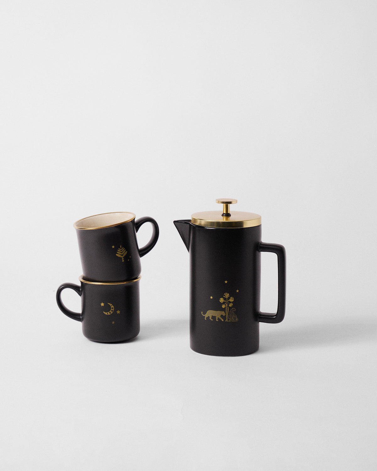 Sindhuraa coffee press and stacked charcoal mugs with gold celestial motifs.