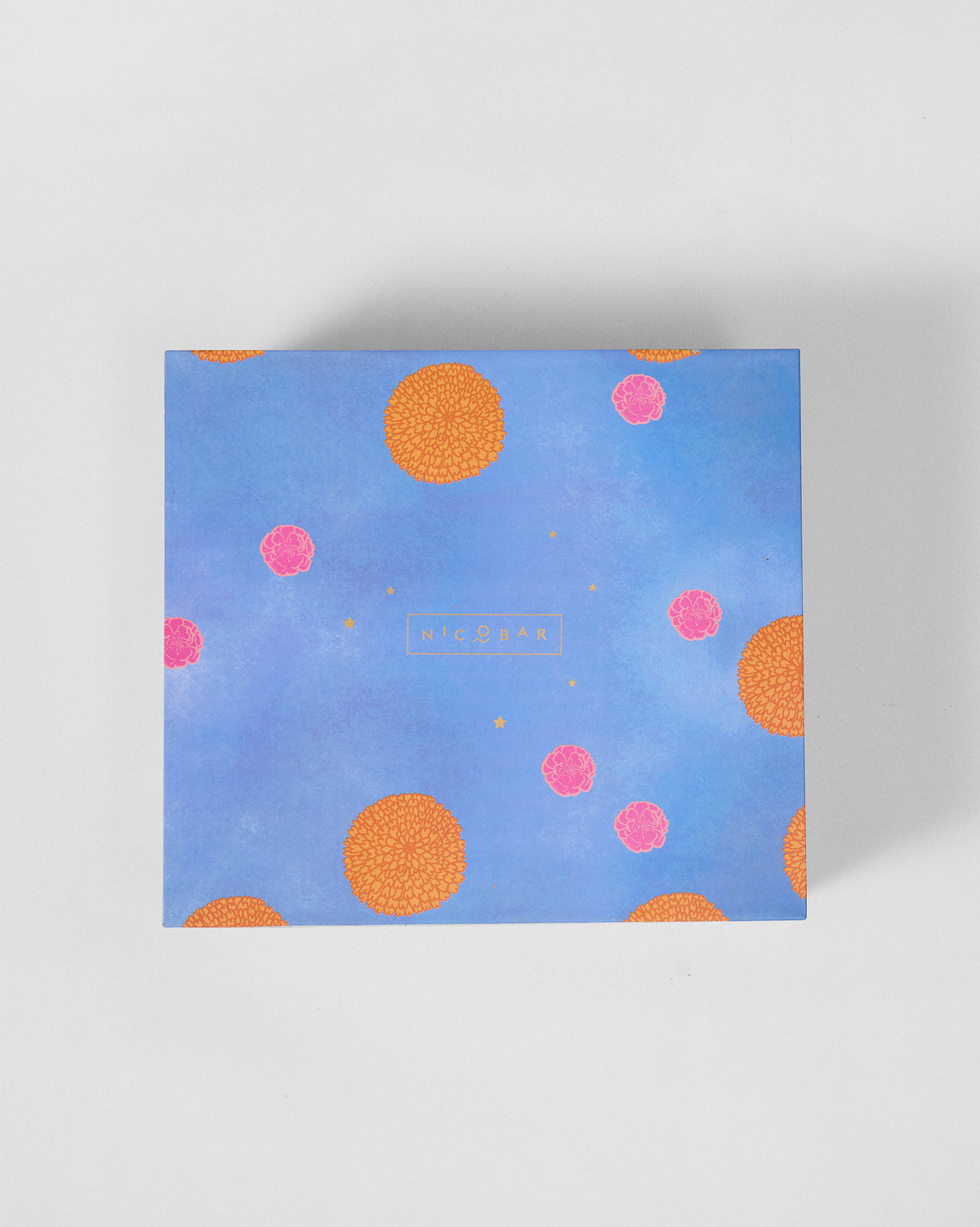 Blue Nicobar gift box lid with orange and pink marigold motifs.