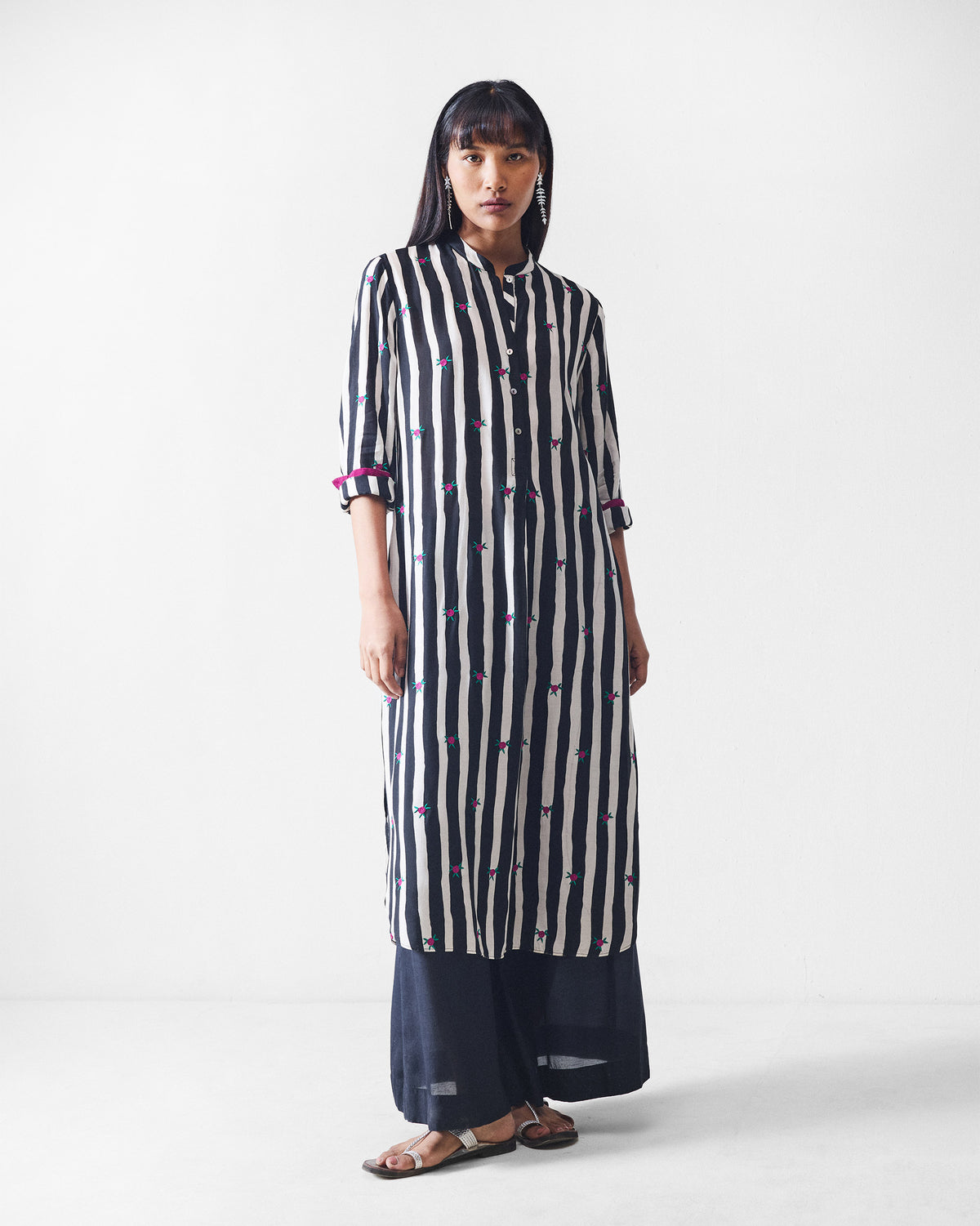 Person wearing a black and beige striped long kurta with pink cuff lining.