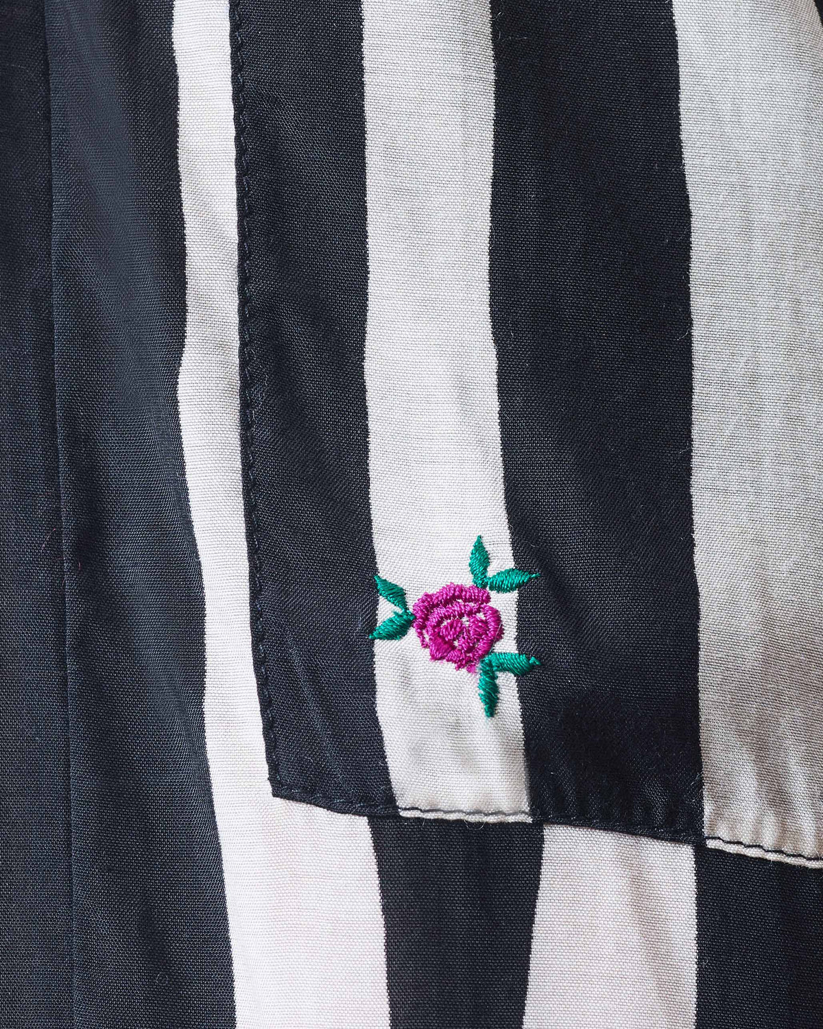 Close-up of black and beige striped Serene pants with a pink rose on the pocket.