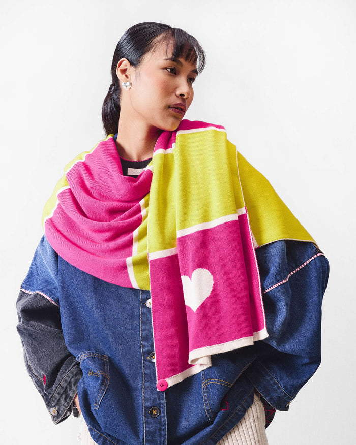 Person wearing the Chromatic Crossroads scarf in pink and yellow with a white heart.