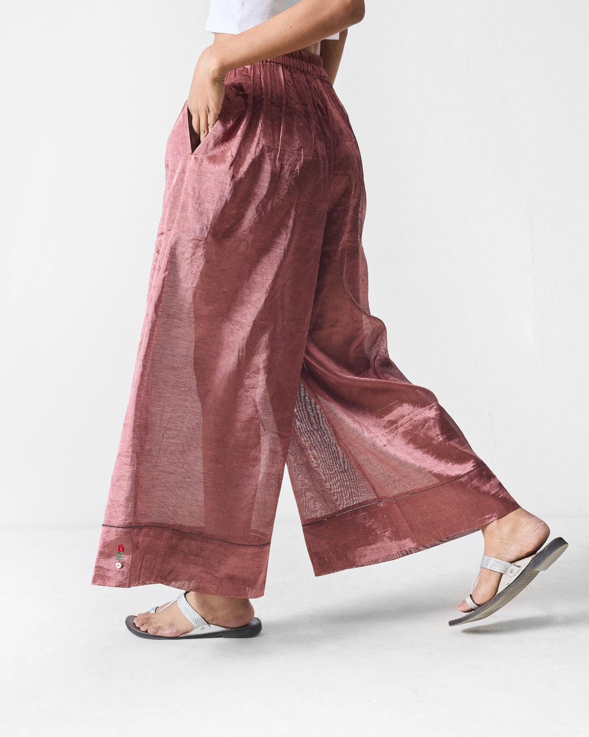 Side view of metallic pink Charisma pants showing a side pocket and flowing drape.