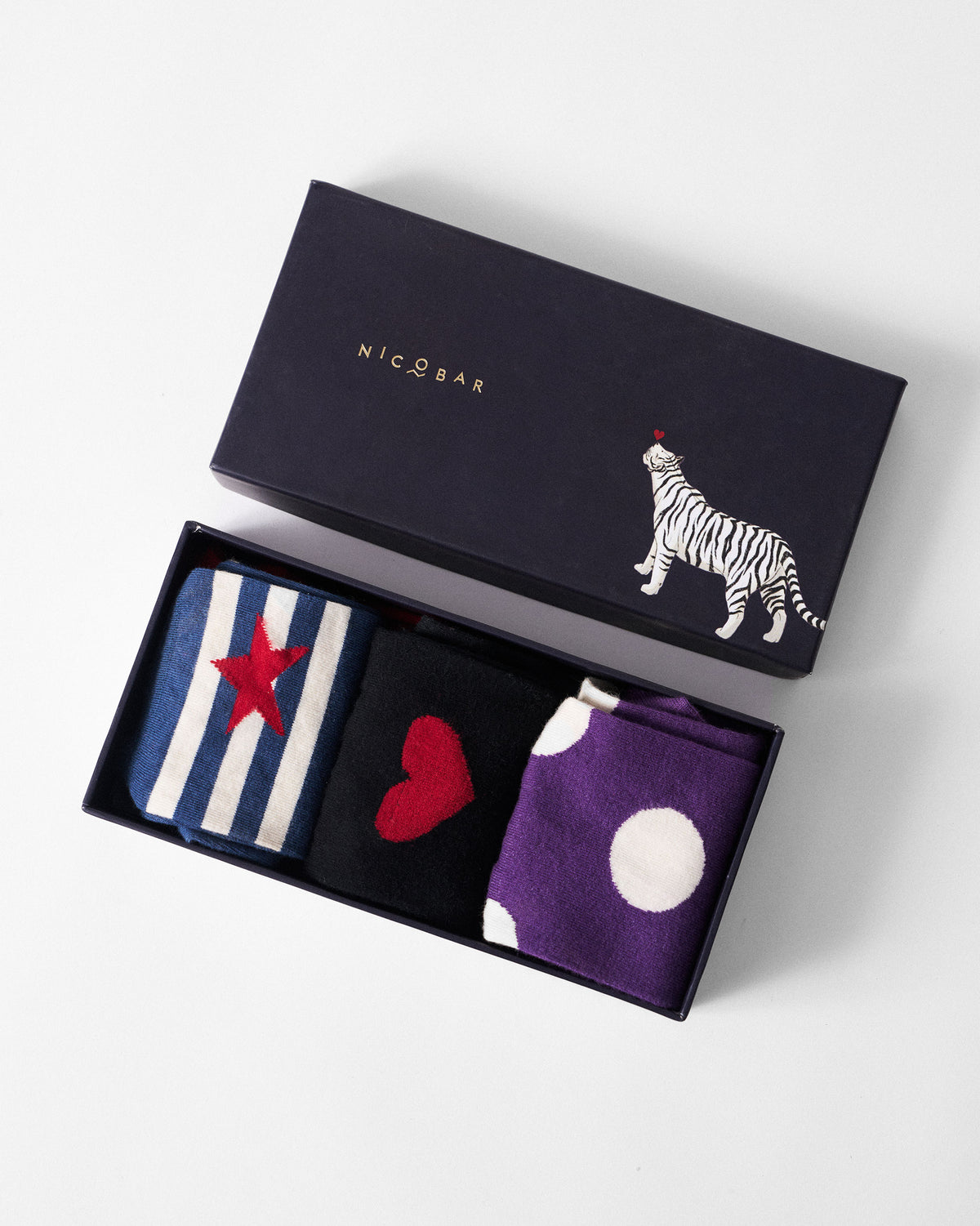Open Nicobar sock gift box with navy star, heart, and polka-dot pairs.