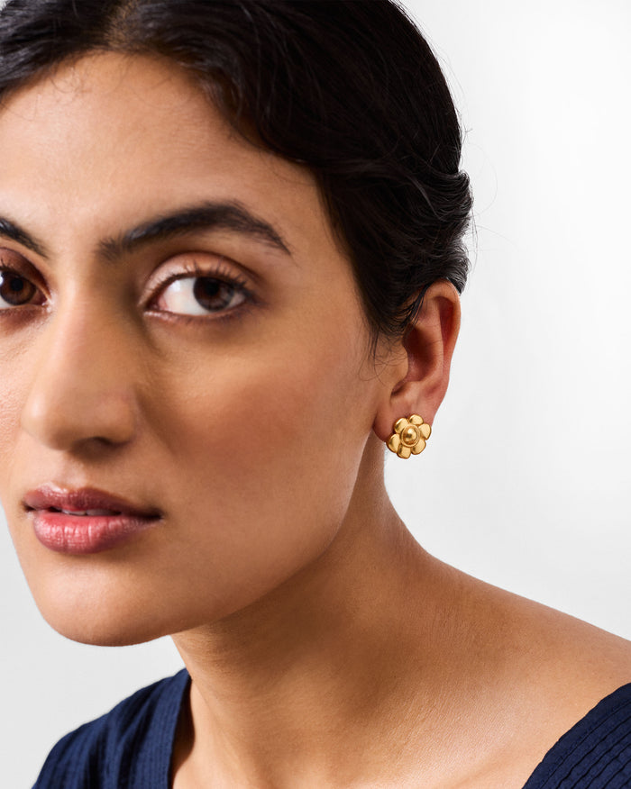 Side profile of a gold Daylily flower stud on a person.