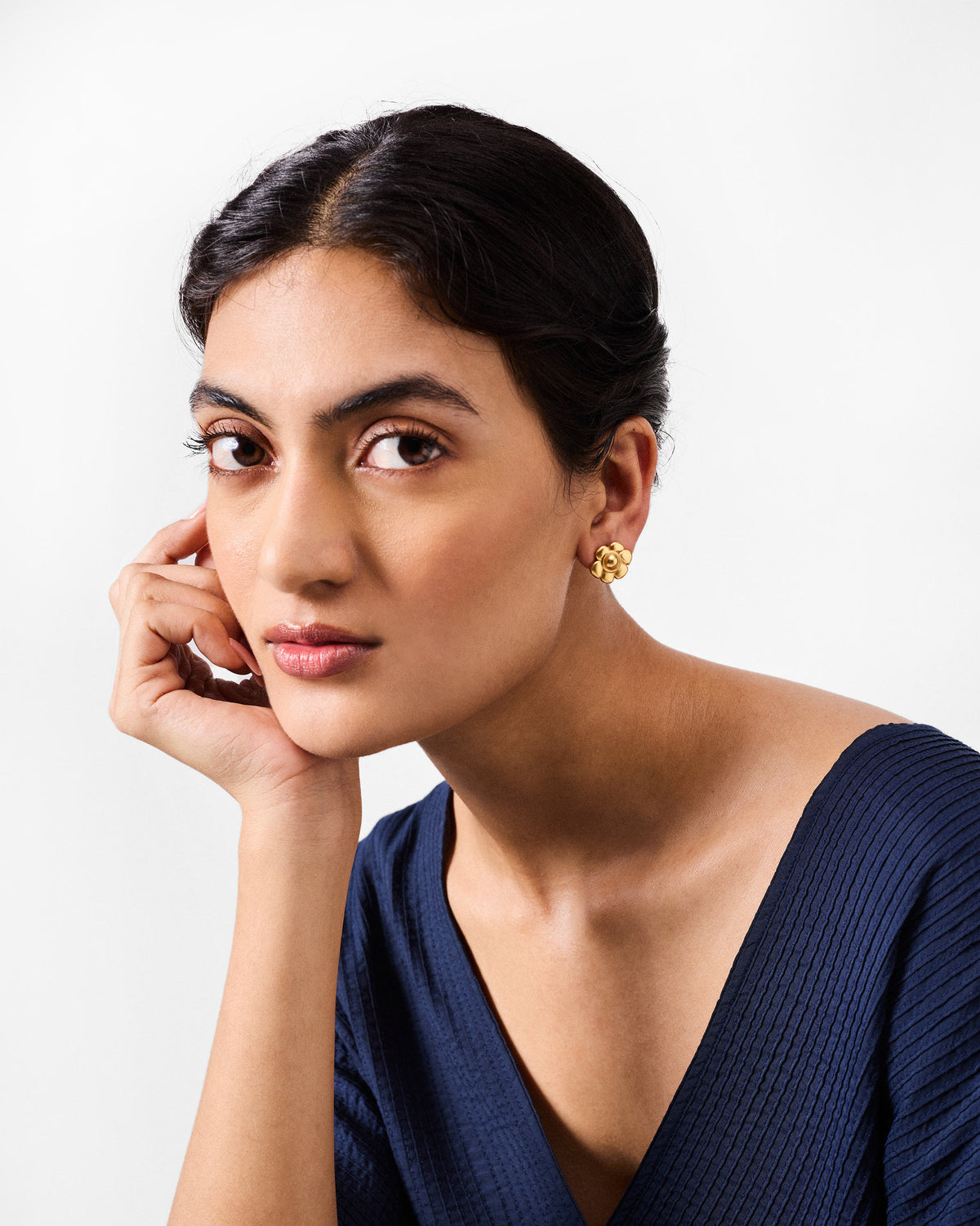Person wearing a gold Daylily flower stud earring.