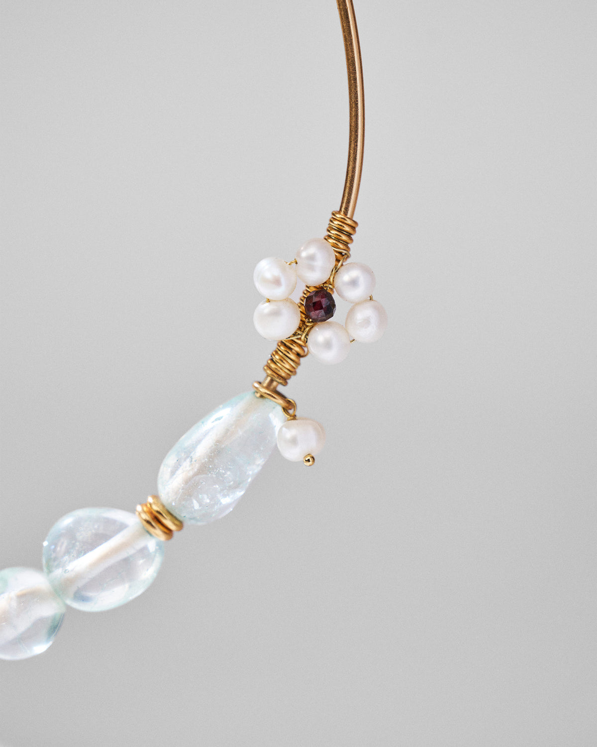 Close-up of a pearl flower charm with a red centre on a Noorani necklace.
