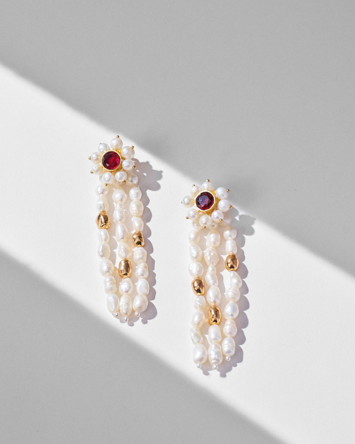 Pair of gold Meher earrings showing pearl strands and red stone flower studs.