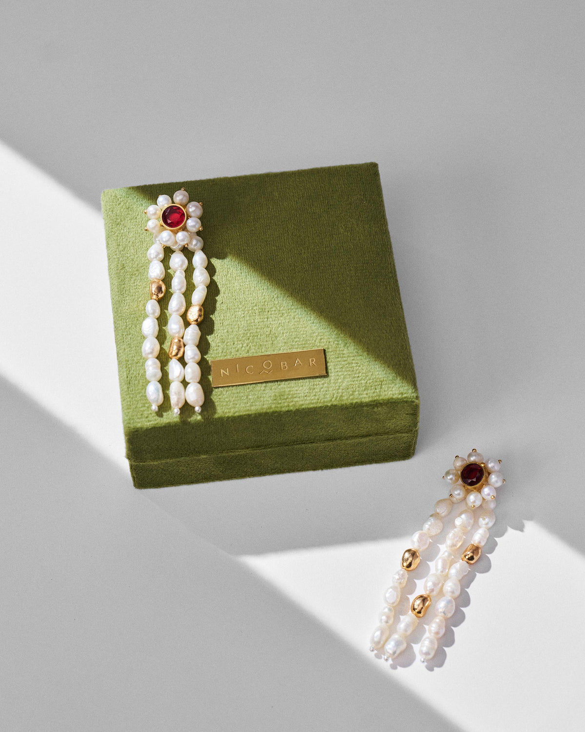 Gold Meher pearl drop earrings on an olive green Nicobar gift box.
