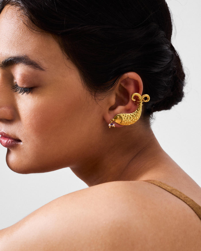 Side profile of gold Dupki fish studs worn as an ear cuff.