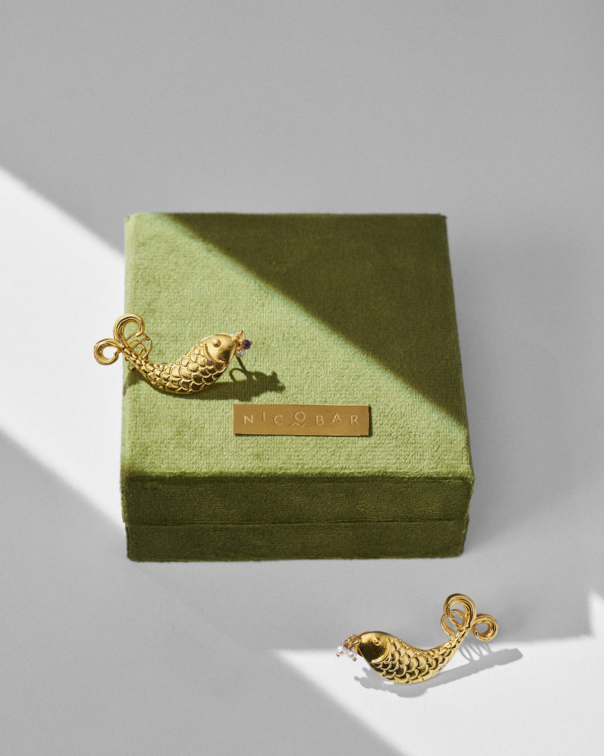 Gold Dupki fish studs with a green Nicobar jewelry box.