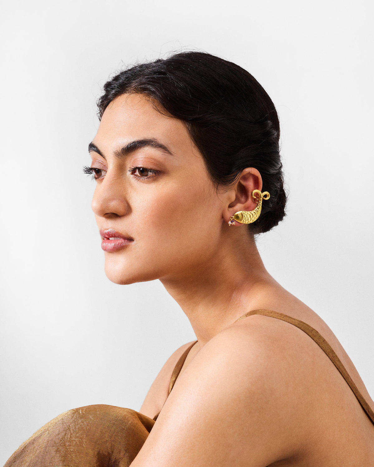Gold Dupki fish studs worn along the ear with a purple stone drop.