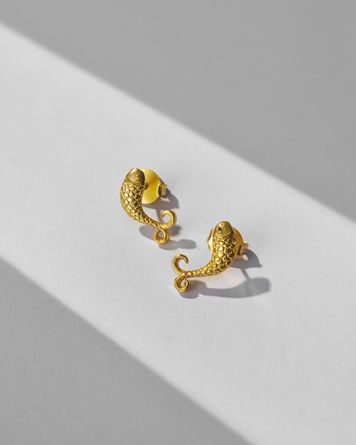 Pair of gold fish Jalpari studs showing scale texture.