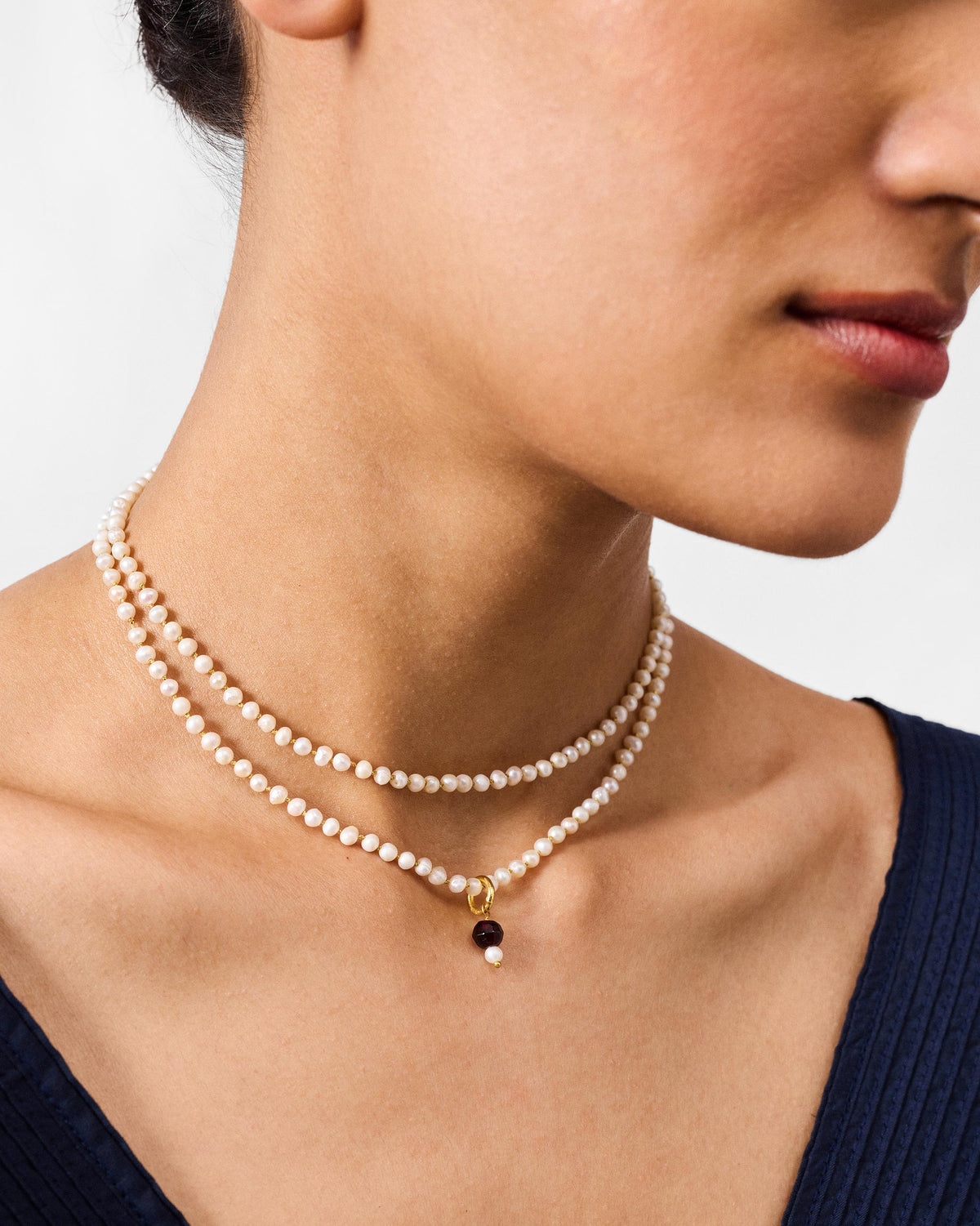Large Chandni pearl necklace worn in two strands with a dark bead pendant.