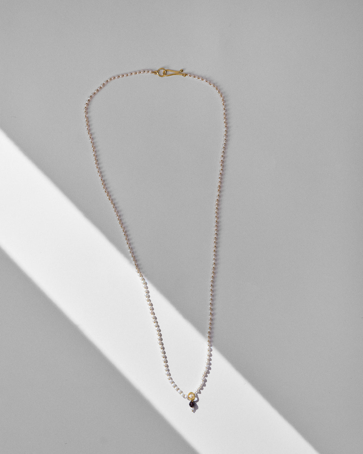Long Chandni large pearl necklace laid flat with a dark drop pendant.
