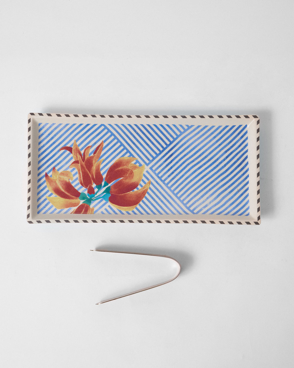Overhead view of the Palash cookie tray and tongs with orange flower print.