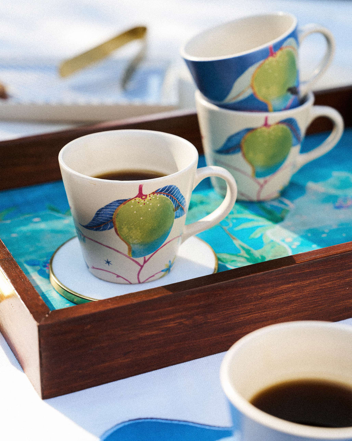 Ambi Espresso Mug with a green mango print filled on a wooden tray.