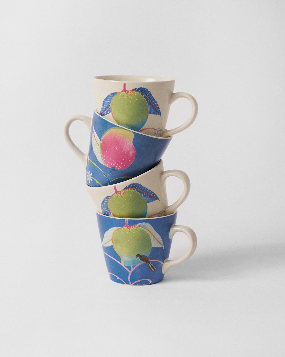 Stack of four Ambi Espresso Mugs with mango prints in cream and blue.
