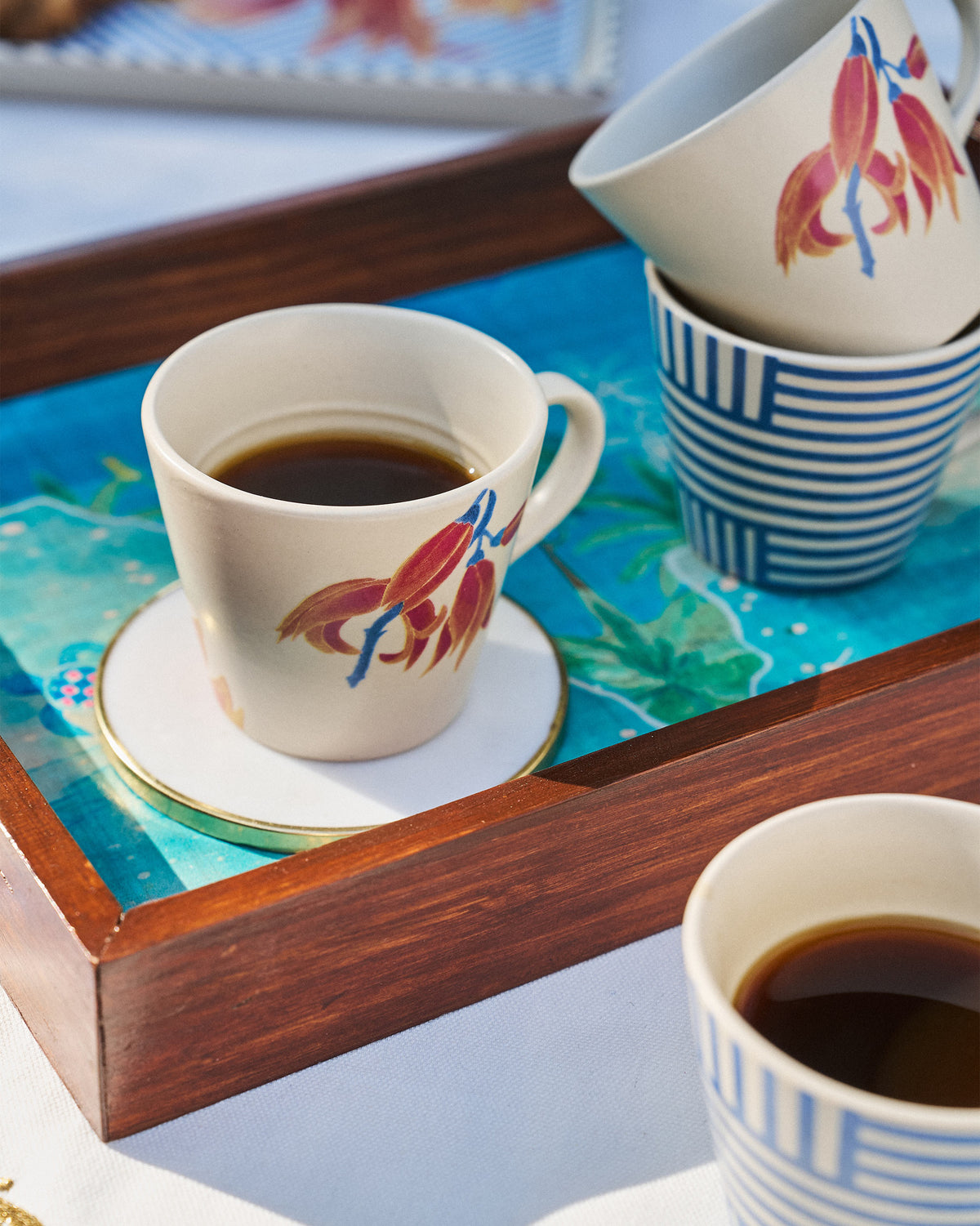 Koel espresso mug with orange palash flowers filled with coffee on a tray.