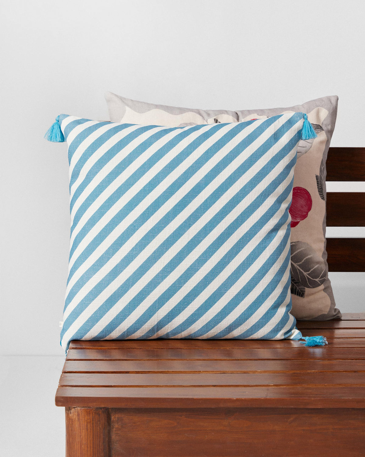 Seb cushion cover with blue and white diagonal stripes and blue tassels.