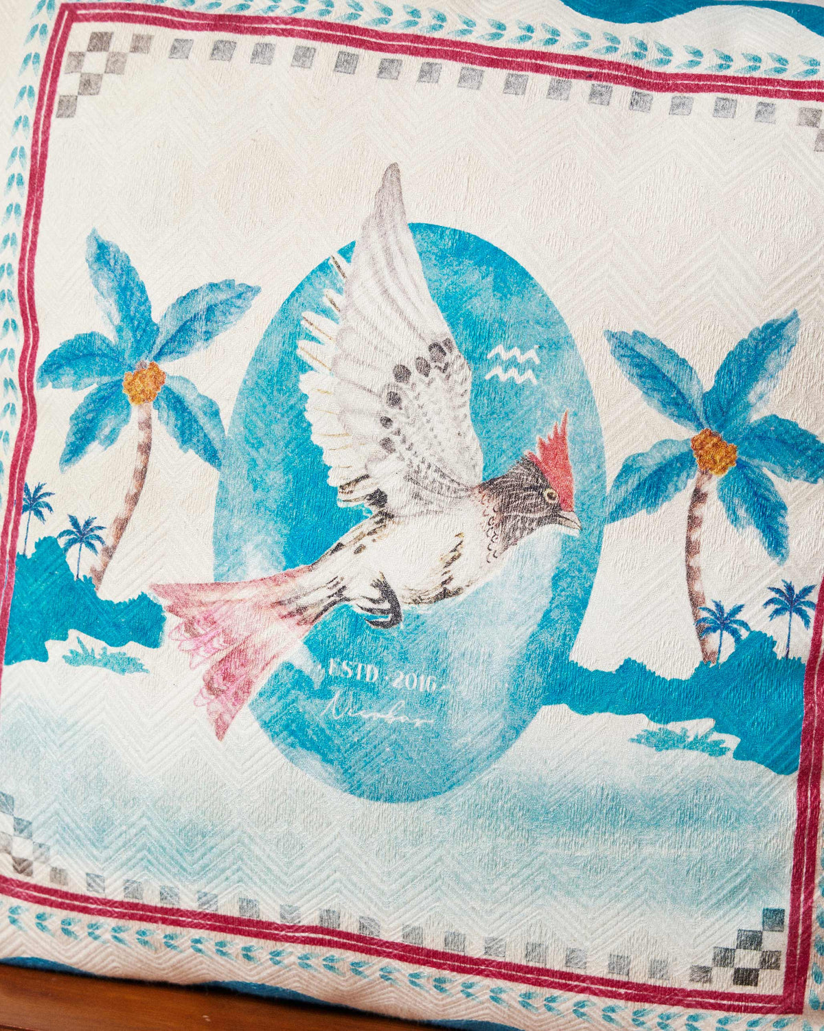 Close-up of Blue Scallop cushion cover showing a flying bird and palm trees.