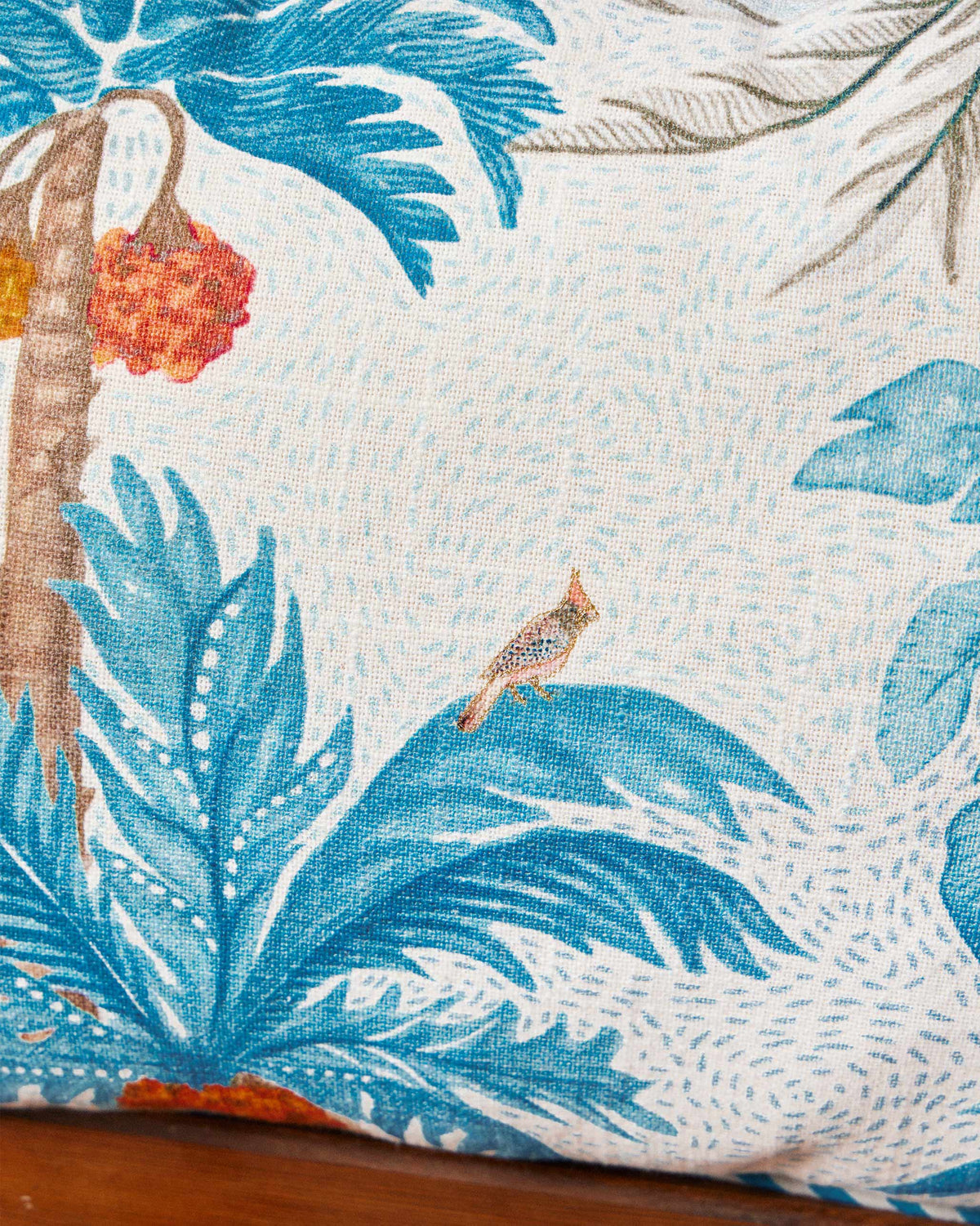 Close-up of a Sindhuraa cushion cover with blue palms and a small bird.