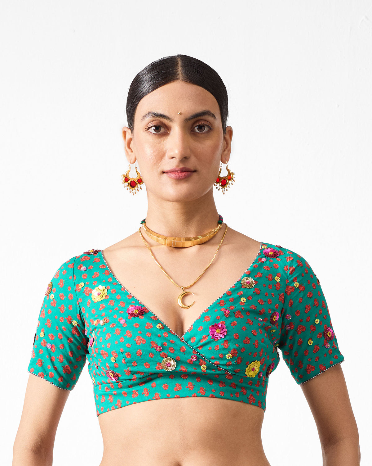 Person wearing a green Saanjh blouse with red and yellow embroidered flowers.