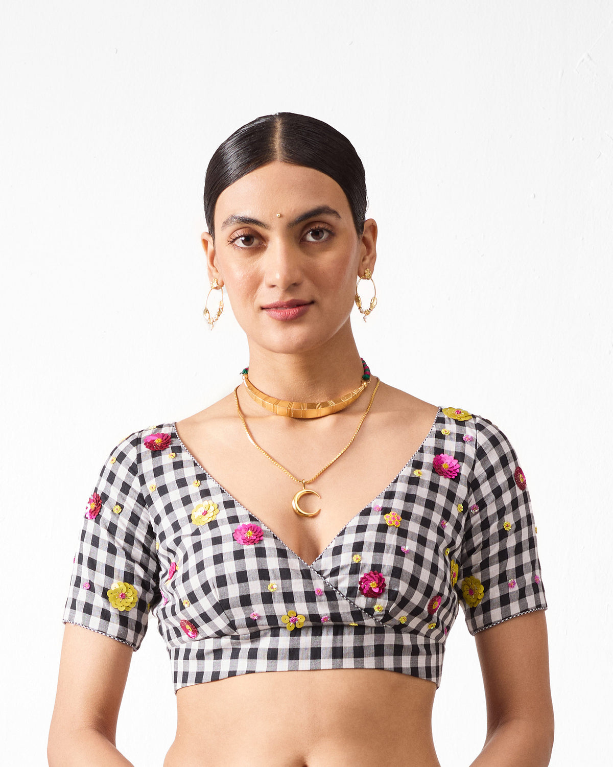 Person wearing a black and white gingham Saanjh blouse with embroidered flowers.