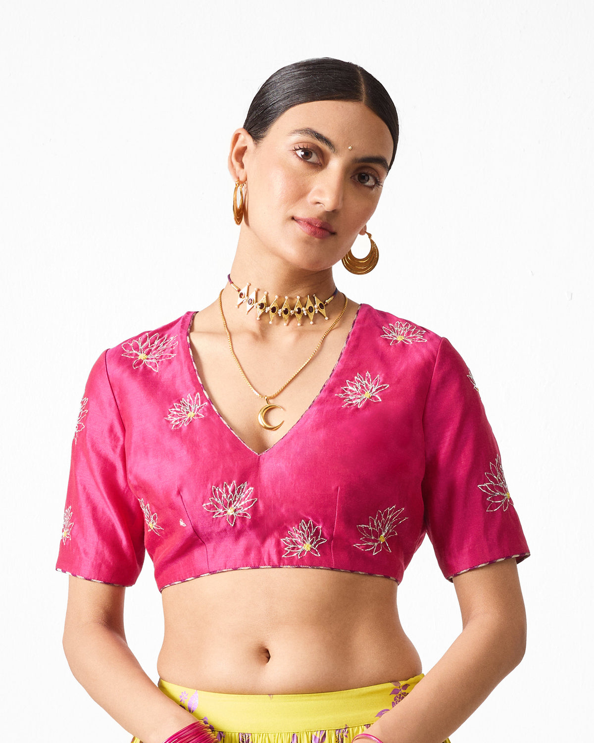 Person wearing a fuchsia Dori blouse with embroidered flower motifs.