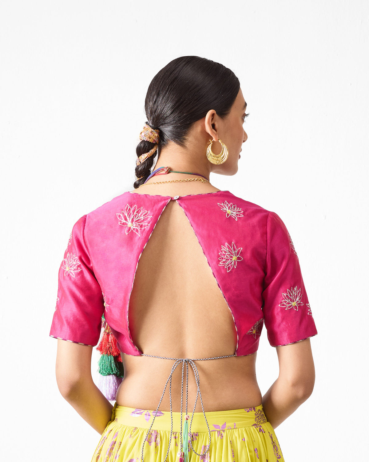Back of a fuchsia Dori blouse with embroidered flowers and an open back.
