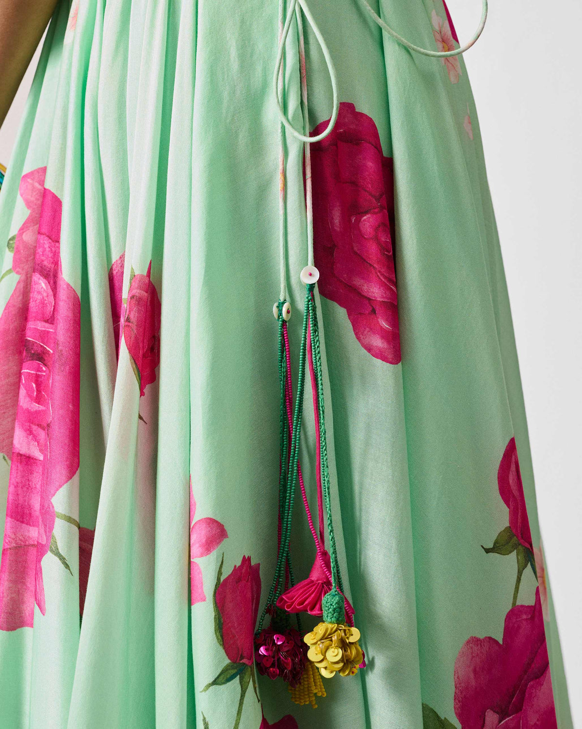 Close-up of sequin tassels at the waist of a sea blue Vaya skirt.