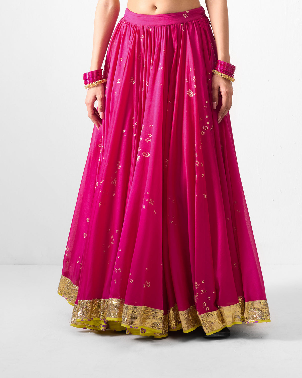 Person wearing a fuchsia Saaya skirt with gold motifs and a gold hem border.