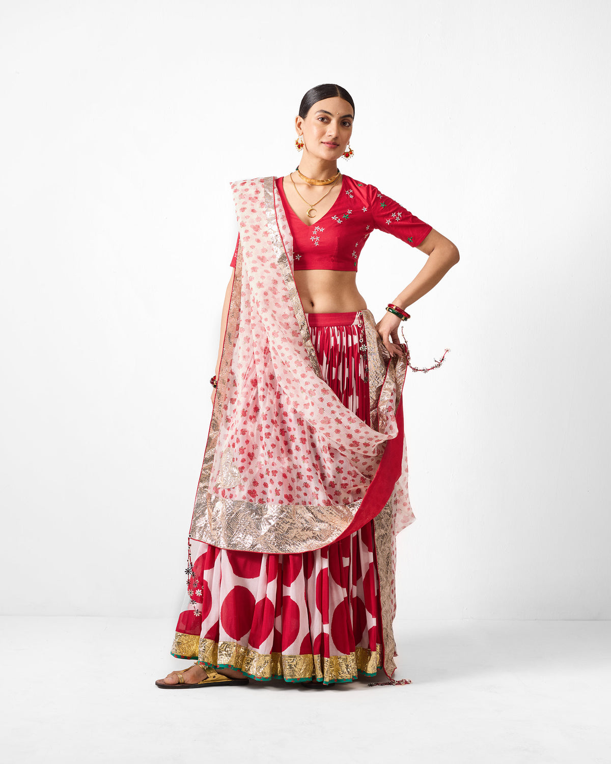Person wearing a red and ivory printed Lehar dupatta with a gold border.