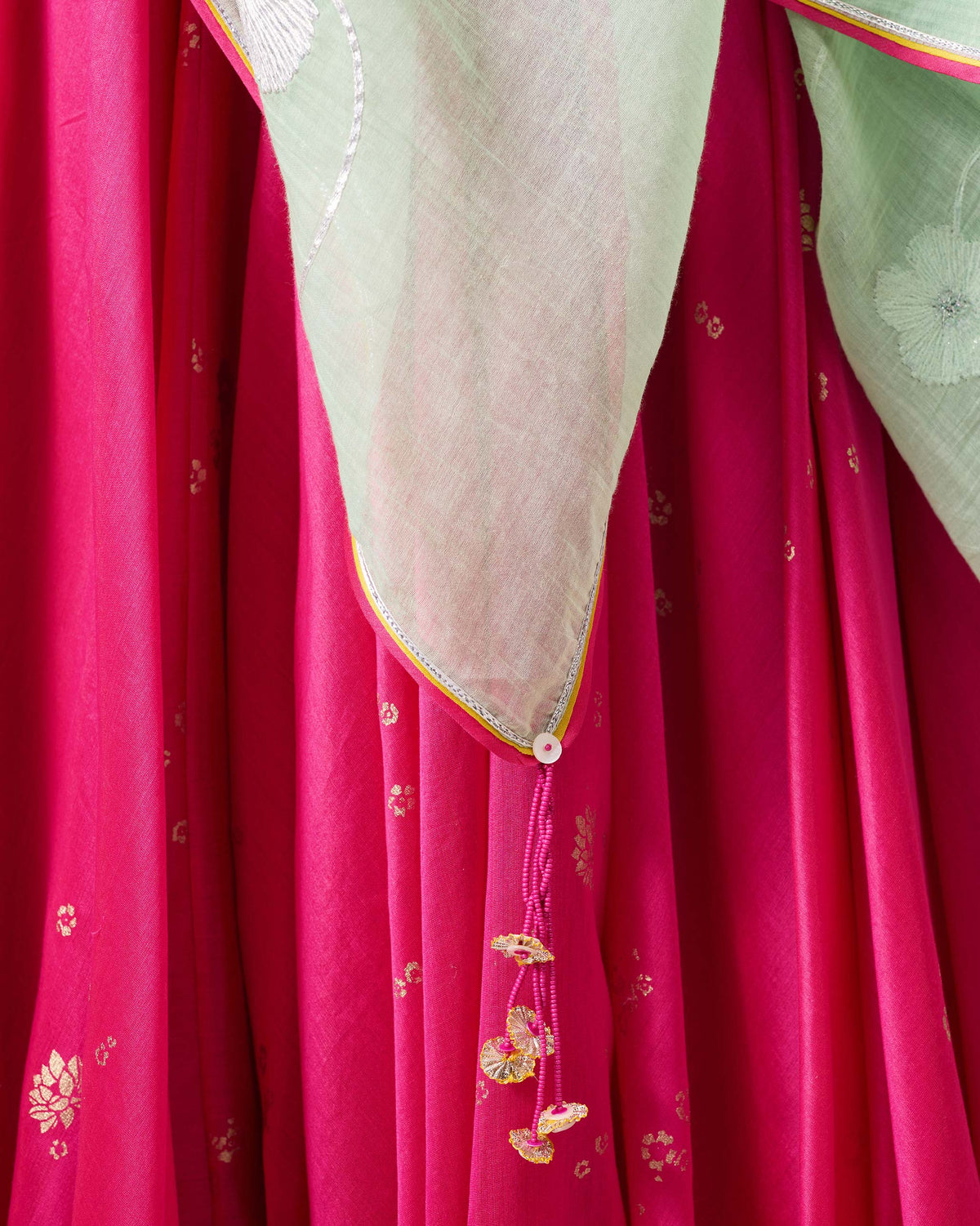 Close-up of sea blue Fiza Dupatta border with pink tassel and floral embroidery.