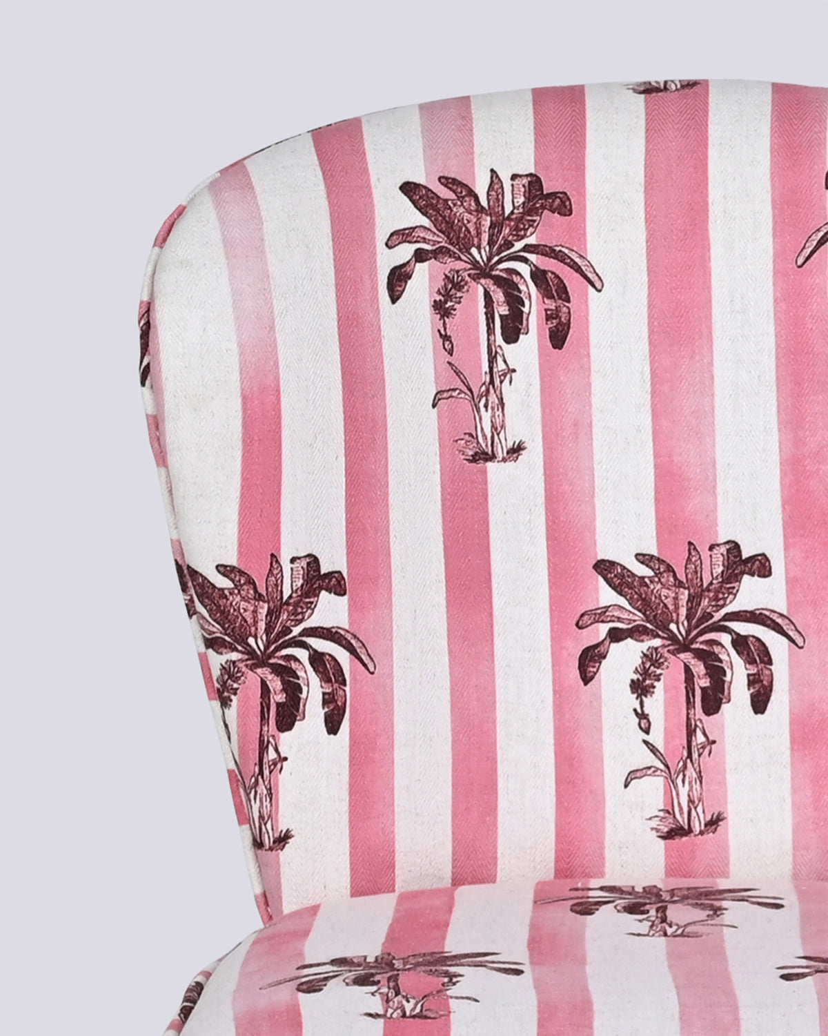 Close-up of Ripple chair fabric with pink stripes and maroon palm trees.