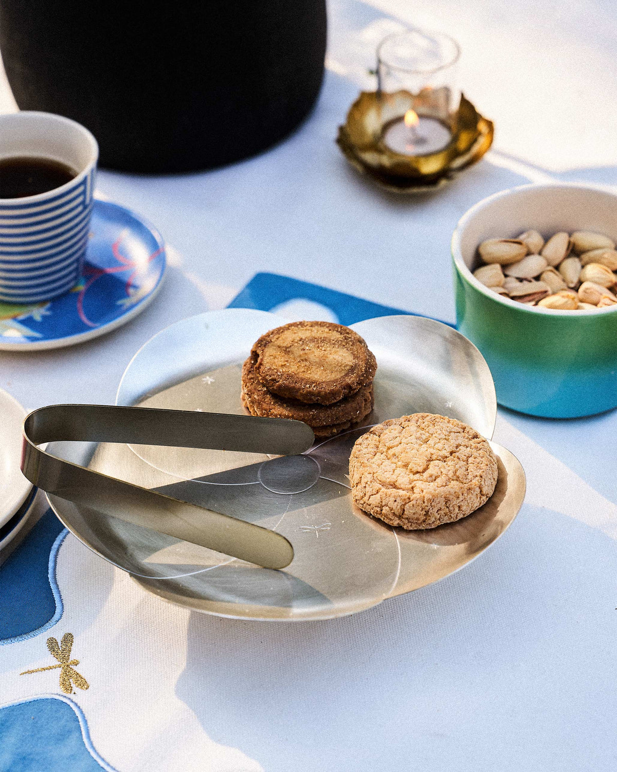 Almond Blossom Platter With Tong holding cookies, with the tong resting on its edge.