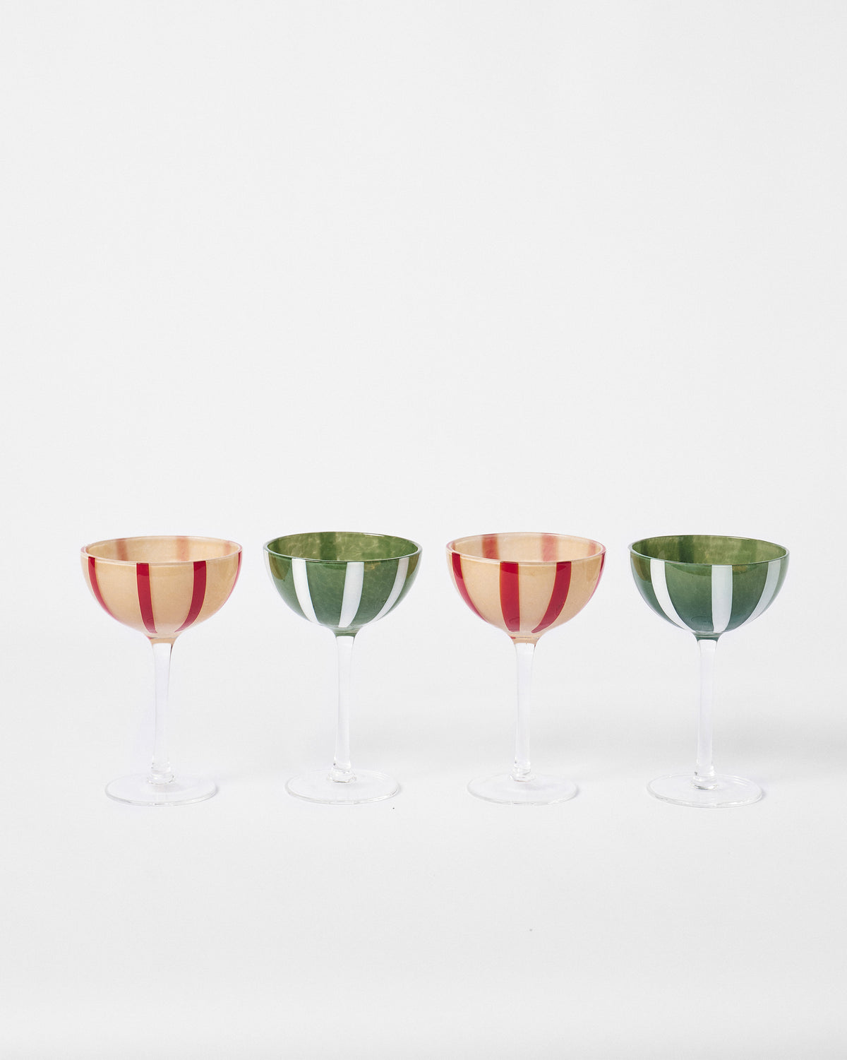 Four Lune cocktail glasses in a row, two with red stripes and two with green.